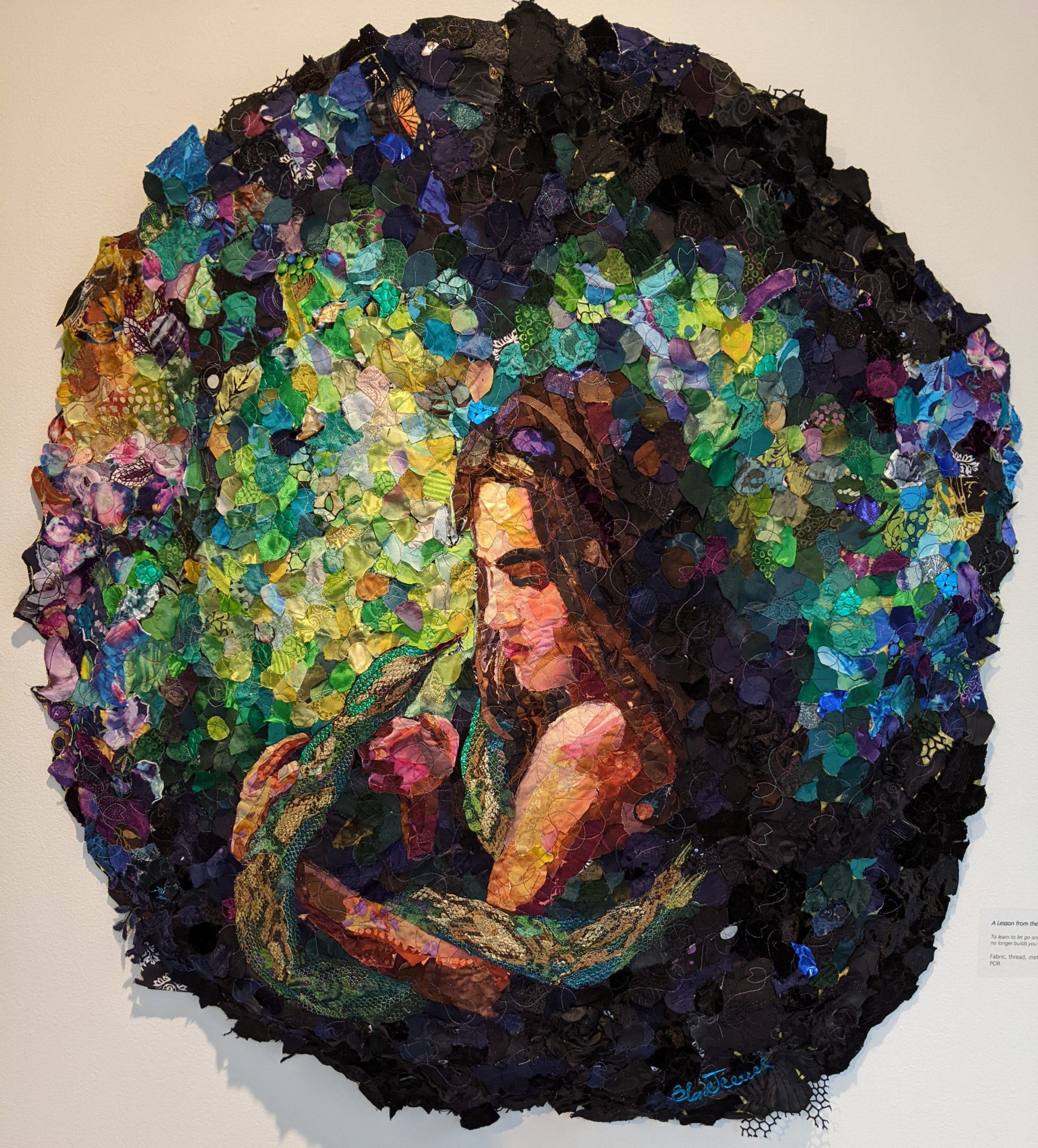 This large, circular piece of textile art shows a young woman with a snake wrapped around her arm.