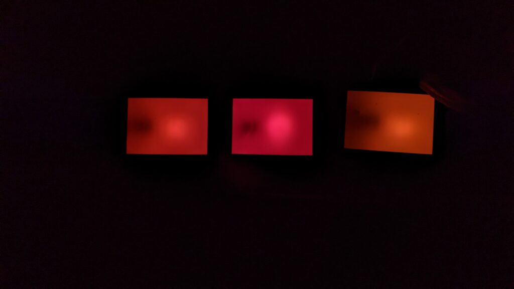 This photo shows three safelights in a darkroom. Two of them are amber colored while one is red.