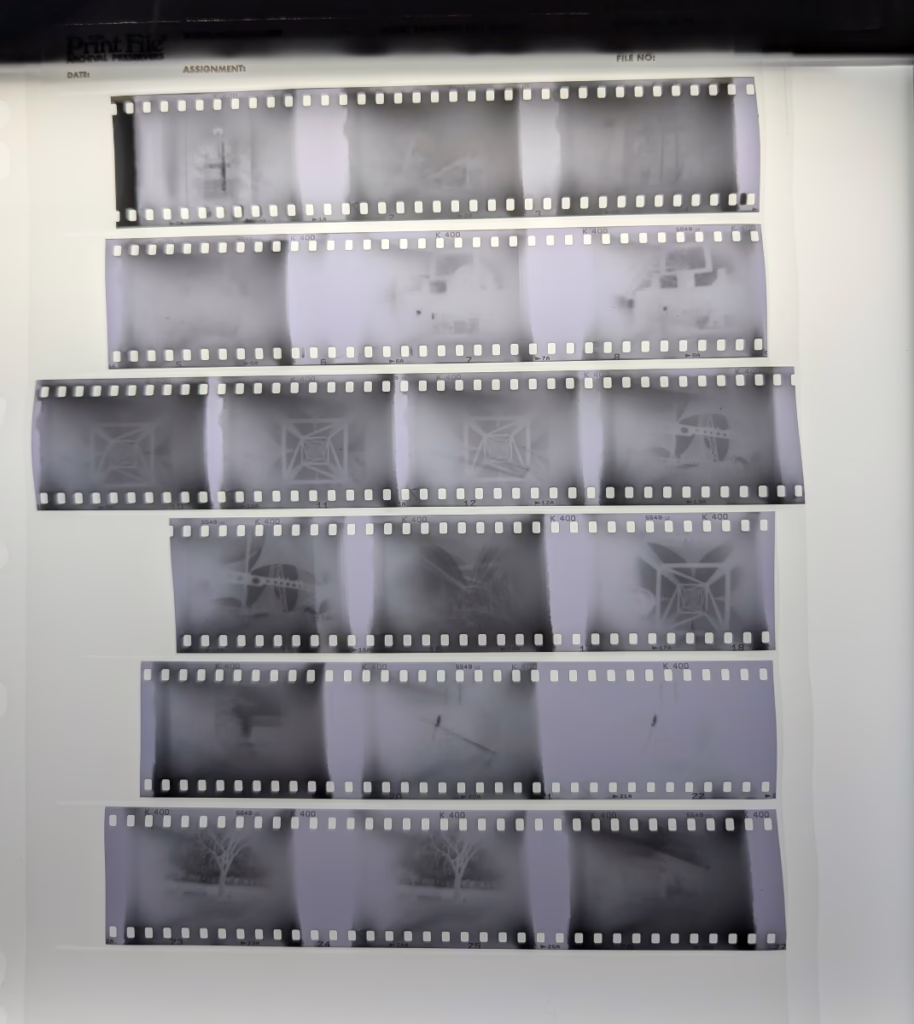 A roll of photographic film is cut into strips. Each photo frame looks uneven and ragged around the edges. Some of the photos are clearly double exposures, and the frames take up 9 sprockets instead of the typical 8.