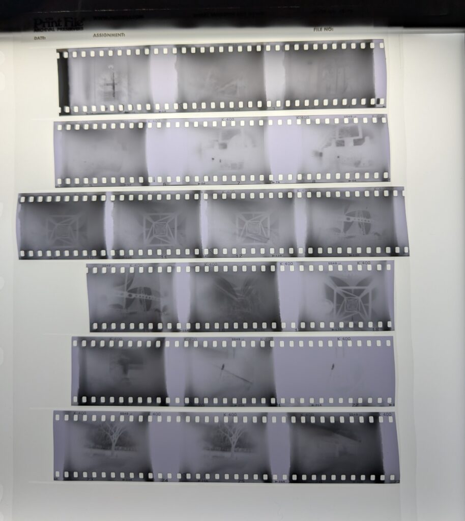 A roll of photographic film is cut into strips. Each photo frame looks uneven and ragged around the edges. Some of the photos are clearly double exposures, and the frames take up 9 sprockets instead of the typical 8.
