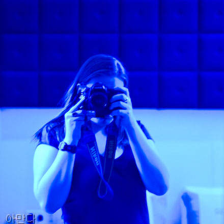 A self portrait, taken in a room bathed in blue light. I'm facing a mirror, and my face is obscured by my camera.