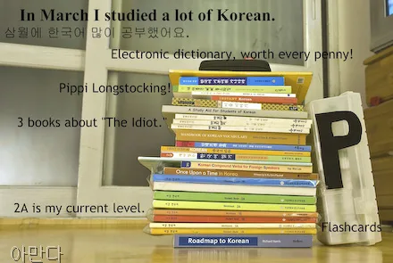 A stack of Korean books sits on the floor of a Korean apartment. A plastic container labeled "flashcards" is leaning against the books. The letter P is attached to the flashcards.