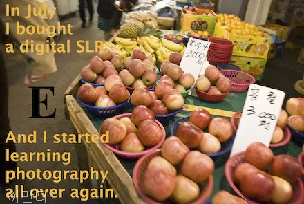 A fruit market is down. Apples are 3,000 South Korean won for a small basket. The letter E is on the photo.