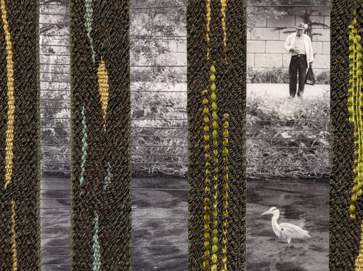 Grandfather and the Heron is a piece of woven textile art. Strips of photographic paper, which show a grandfather standing near a stream looking at a heron in the water, are woven with olive green yarn, strips of silk ribbon in greens and blues, velvet ribbon in two shades of green, and metallic gold embroidery floss.